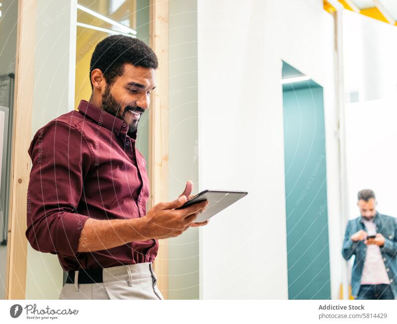 Lächelnder Mann im Hemd bei der Arbeit mit einem Tablet in einem Coworking Business Arbeiter Lifestyle Manager Geschäftsmann Tablette professionell modern