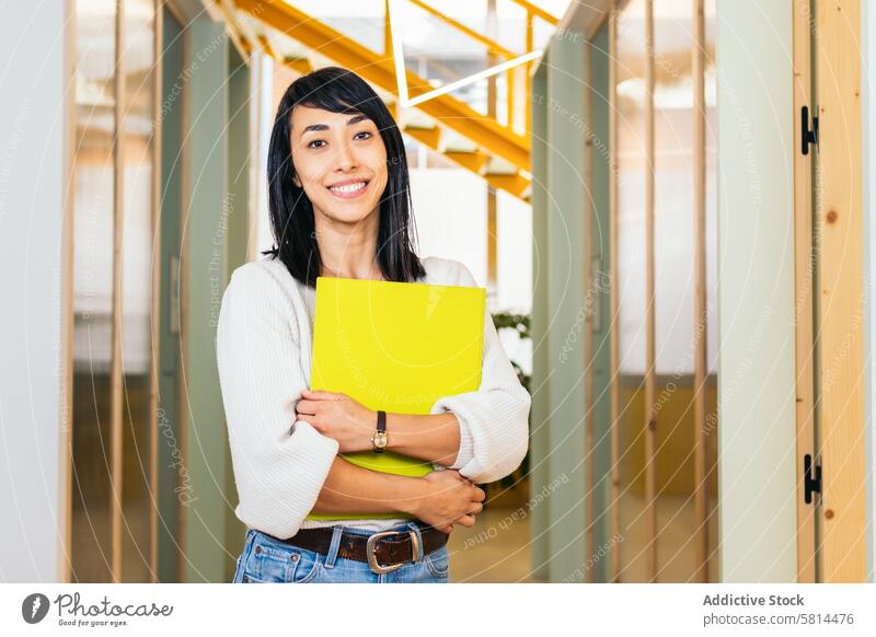 Porträt einer lächelnden asiatischen Frau, die in die Kamera schaut und einen Ordner in einem modernen Büro hält Geschäftsfrau Arbeiter Lifestyle Manager