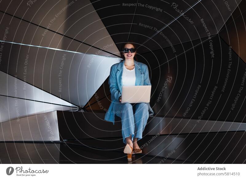 Frau mit Sonnenbrille beim Surfen auf dem Laptop im Studio futuristisch 3d Browsen Atelier modern Design online Internet Apparatur benutzend Gerät elegant Wand