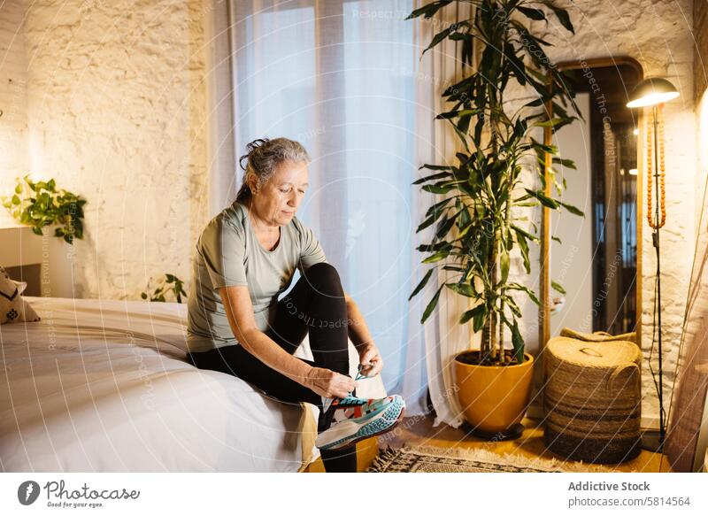 Ältere Frau macht sich bereit zum Laufen 65-69 Jahre nur eine Seniorin aktiv Aktive Senioren Erwachsener gealtert allein Schlafzimmer Körperpflege körperbewusst