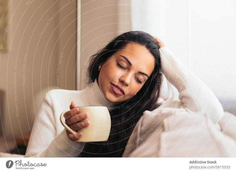 Den Morgen zu Hause genießen: Junge Frau trinkt Kaffee Erholung heimwärts Fenster Sofa im Innenbereich gemütlich Gelassenheit Ruhe Komfort friedlich Lifestyle
