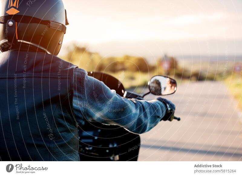 Motorradfahrer bei Sonnenuntergang auf der Landstraße Biker Mitfahrgelegenheit Lederjacke Schutzhelm Wegsehen Freizeit Erholung Transport Hobby Lifestyle Reise