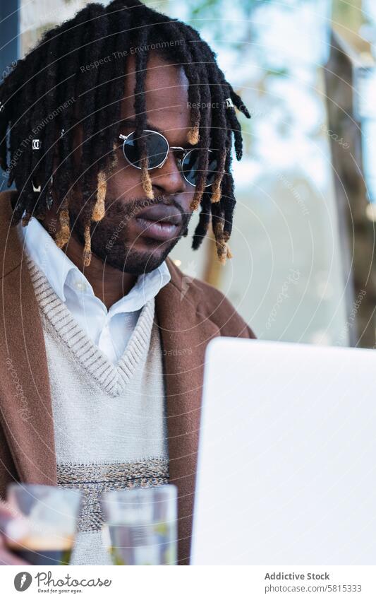 Ernster schwarzer Mann mit Espresso und einem Glas Wasser in einem Cafe Café Laptop Tippen trinken Kaffee Straße männlich ethnisch Afroamerikaner Browsen