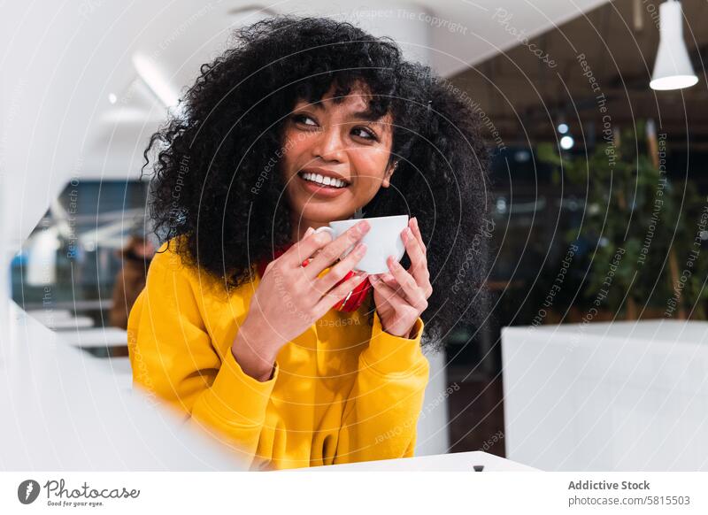 Lächelnde ethnische Frau trinkt Kaffee in einem Cafe Café Inhalt heiter Kantine Stil Optimist Glück jung positiv trinken benutzend Tasse Dame froh Afro-Look
