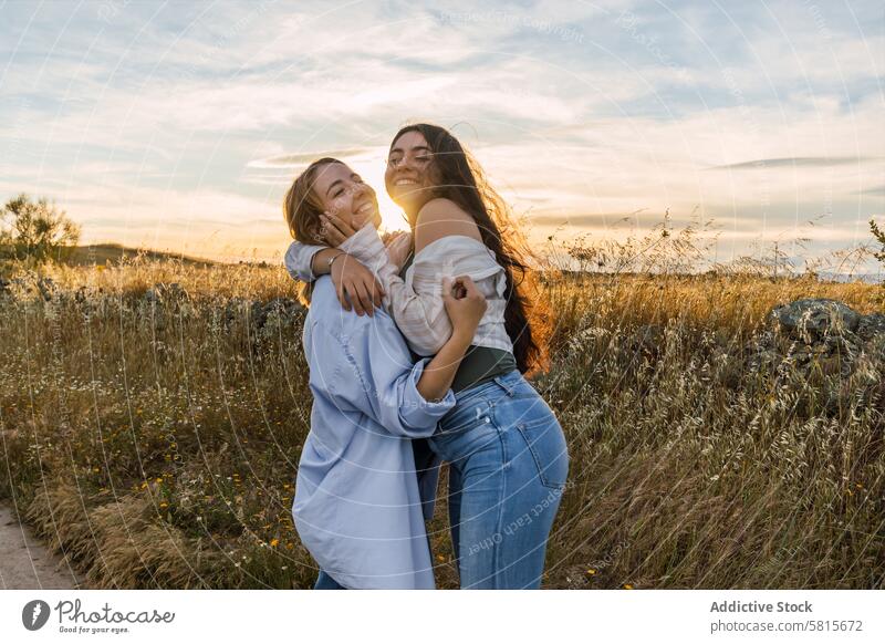 zwei junge Frauen umarmen sich bei Sonnenuntergang auf einer Wiese Paar Zusammensein Liebe Romantik Natur Familie Glück Feld Lifestyle Partnerschaft