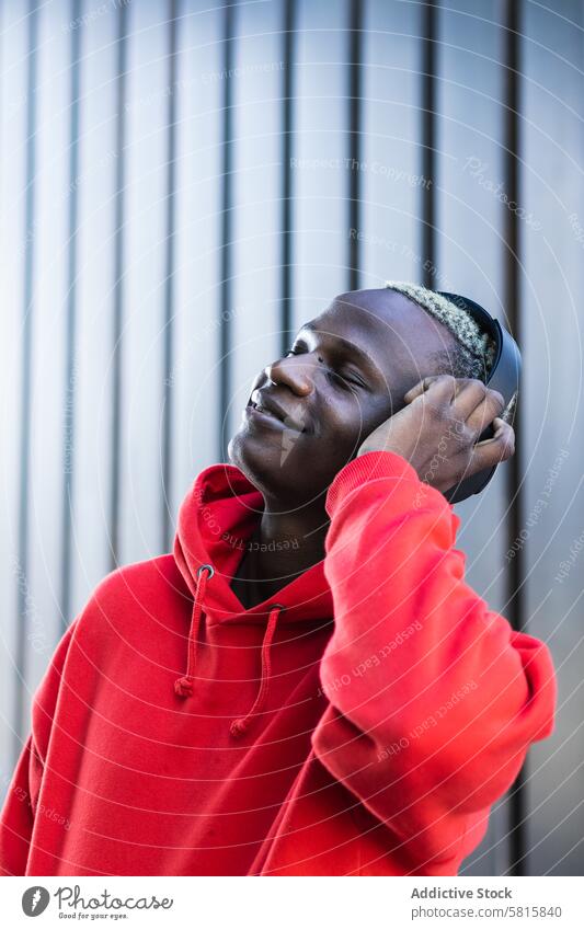 Zufriedener schwarzer junger Mann, der mit geschlossenen Augen über Kopfhörer Musik hört zuhören Augen geschlossen Lächeln genießen meloman trendy Glück
