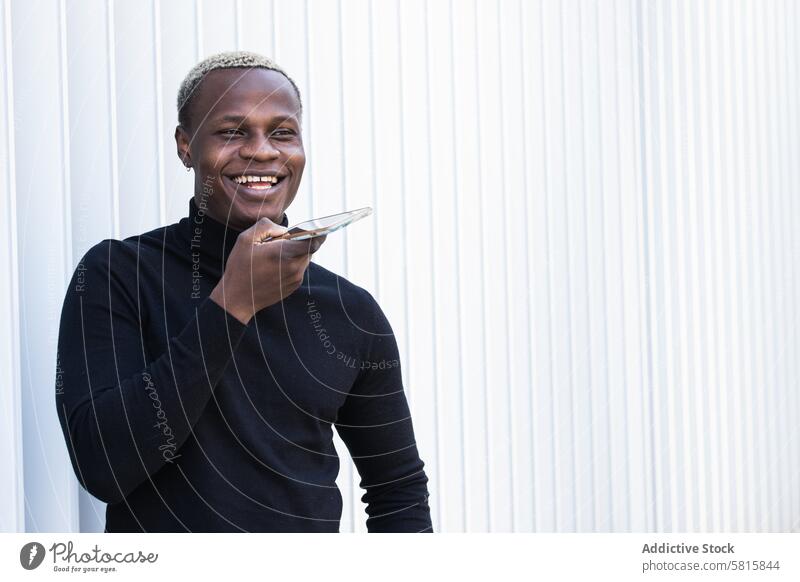 Positiver junger ethnischer Mann, der eine Sprachnachricht auf einem Smartphone aufnimmt Stimme Nachricht Lächeln heiter reden Gespräch Stil positiv