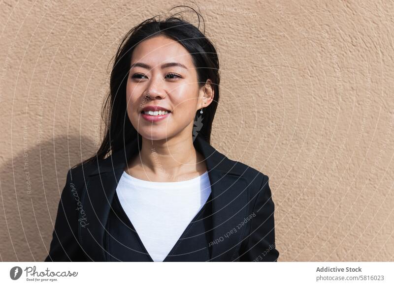 Asiatische brünette Frau mit langen Haaren lehnt an der Wand und schaut weg Japanisch asiatisch Asien jung Model Chinesisch Stil attraktiv Dame Straße modern