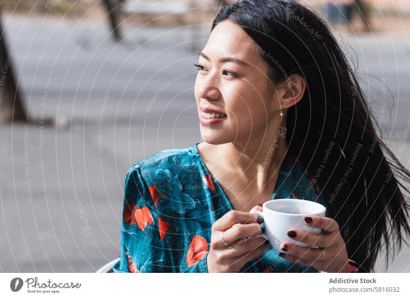 Langhaarige brünette asiatische Frau trinkt einen Kaffee auf der Terrasse eines Cafés Menschen Werkstatt Chinesisch Kaffeehaus Tasse Person trinken heiß