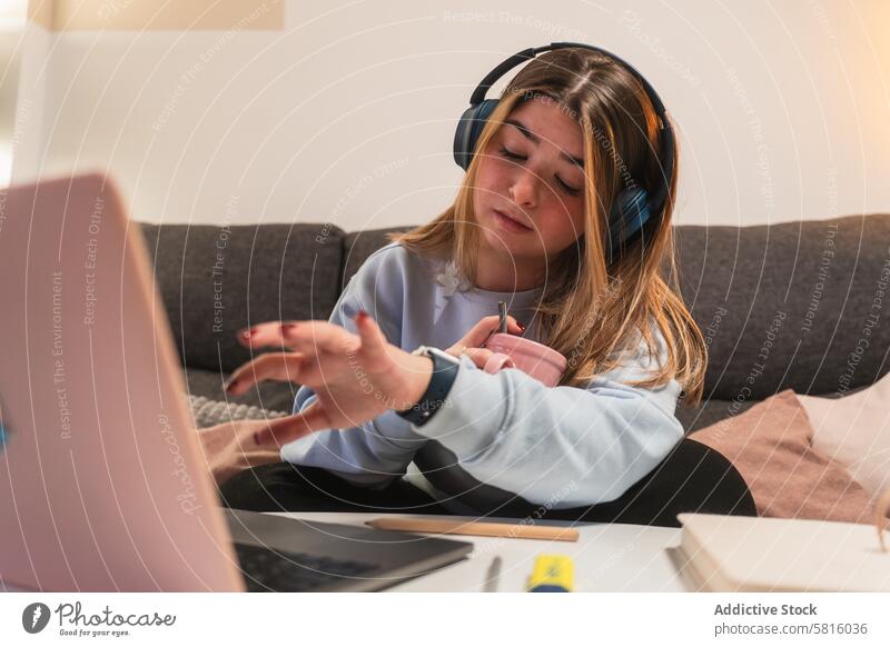 Junge Frau beim Multitasking, während sie von zu Hause aus arbeitet jung heimwärts Kopfhörer Laptop verwirrt Ausdruck arbeiten Technik & Technologie Sofa