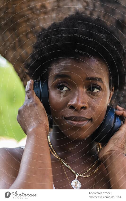 Schwarze Frau, die mit Kopfhörern Musik hört Glück zuhören Gesang benutzend Drahtlos Melodie genießen Gerät Afrohaar Spaß Audio Optimist Lächeln Freude Dame