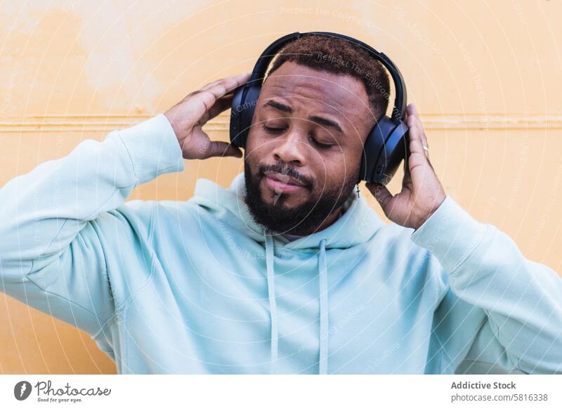 Optimistischer schwarzer Hipster, der mit Kopfhörern Musik hört Mann Glück zuhören genießen heiter Vollbart Drahtlos Erwachsener Afroamerikaner ethnisch