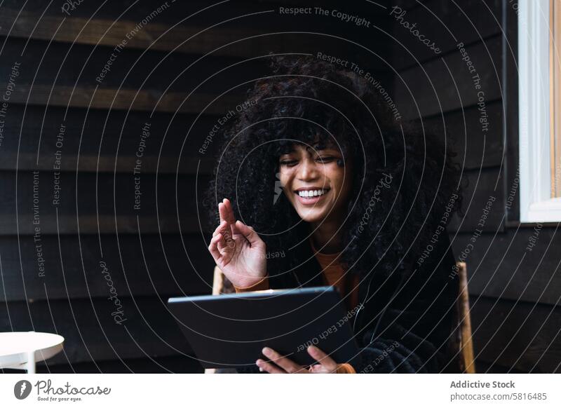 Lächelnde schwarze Frau mit Tablet auf der Veranda Tablette Videoanruf benutzend Terrasse Haus sich[Akk] entspannen ruhen Wochenende Freizeit Kälte Porträt