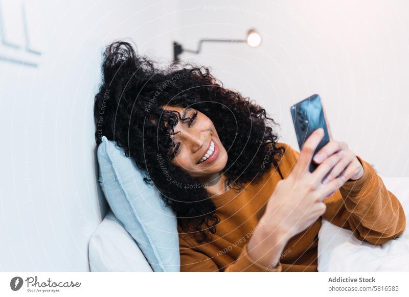 Glückliche schwarze Frau mit Mobiltelefon im Bett Smartphone benutzend wach Morgen Wochenende zu Hause sich[Akk] entspannen ruhen Afroamerikaner Mobile Telefon