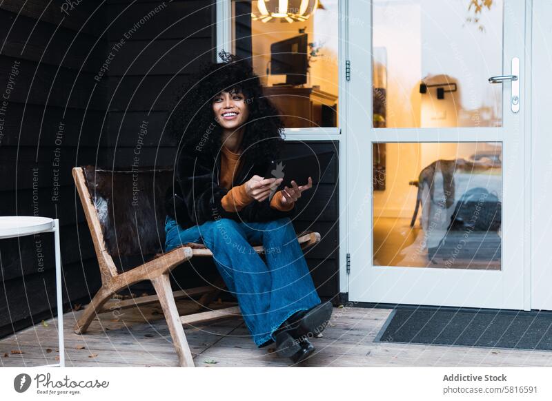 Lächelnde schwarze Frau mit Tablet auf der Veranda Tablette benutzend Terrasse Haus sich[Akk] entspannen ruhen Wochenende Freizeit Kälte Porträt Afroamerikaner