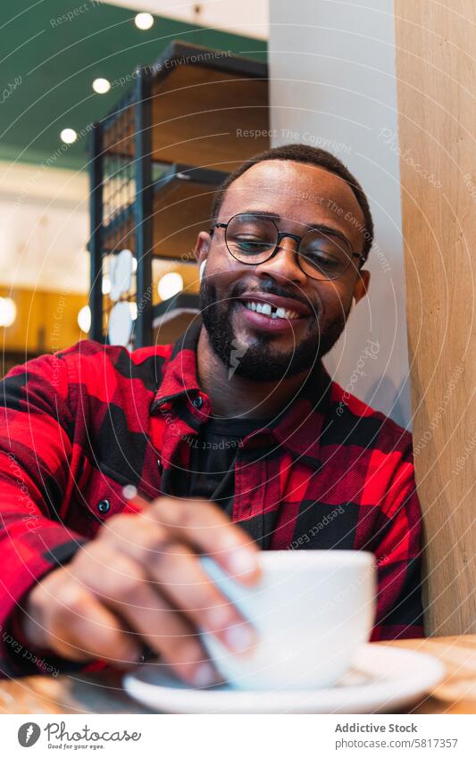 Lächelnder schwarzer Mann mit einer Tasse Kaffee im Cafe Café Kopfhörer benutzend Heißgetränk Kaffeepause Musik ruhen sich[Akk] entspannen männlich