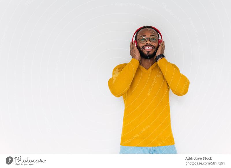 Schwarzer Mann, der mit Kopfhörern Musik hört Lächeln benutzend zuhören sich[Akk] entspannen ruhen Kälte Gesang Freude meloman männlich Glück schwarz froh