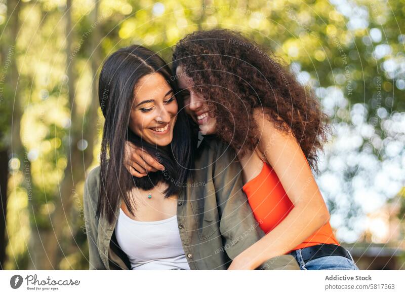 zwei junge Frauen sitzen umarmend in einem Park Paar Glück Zusammensein Liebe Menschen romantisch Partnerschaft Umarmung Mädchen Lifestyle Sitzen lässig schön