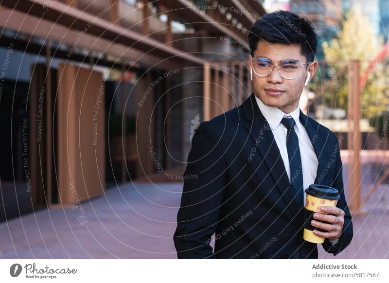 Hübscher ethnischer Geschäftsmann mit Kaffee zum Mitnehmen in der Stadt Imbissbude Großstadt gutaussehend Anzug Unternehmer maskulin Straße männlich asiatisch