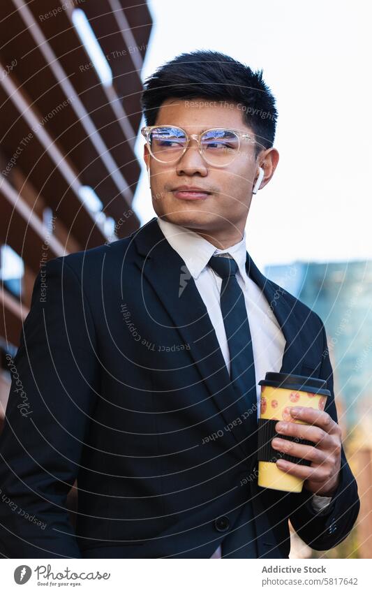 Hübscher ethnischer Geschäftsmann mit Kaffee zum Mitnehmen in der Stadt Imbissbude Großstadt gutaussehend Anzug Unternehmer maskulin Straße männlich asiatisch