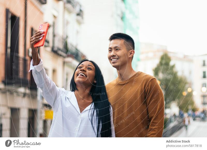 Asiatischer Mann und lateinamerikanische Frau machen ein Selfie mit Smartphone asiatisch hispanisch Partnerschaft Liebe Zusammensein Menschen Paar Datierung