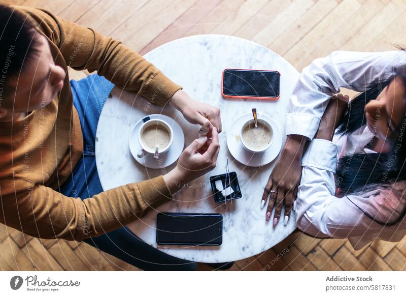 Overhead-Aufnahme von zwei Menschen bei einer Verabredung, die Kaffee trinken Tisch Draufsicht Tasse Kaffeehaus Café Termin & Datum Lifestyle Konzept Smartphone