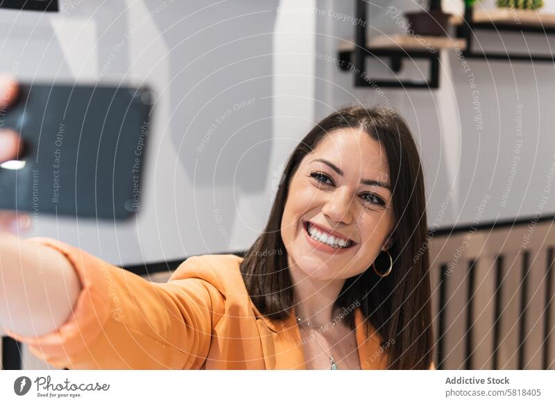 Fröhliche Frau, die in einem Café ein Selfie mit ihrem Smartphone macht Kälte Spaß haben Lächeln Selbstportrait Telefon Mobile benutzend positiv Apparatur