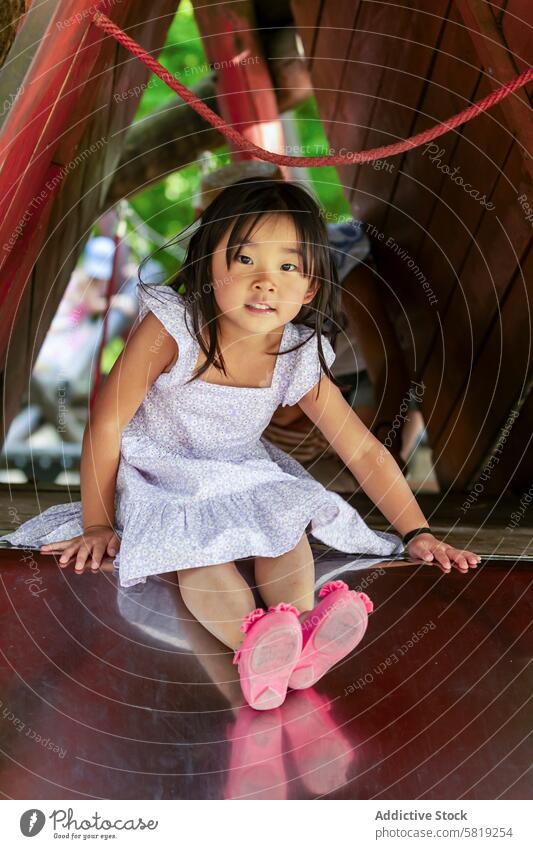 Asiatisches Mädchen spielt auf einer Rutsche im Familienurlaub asiatisch Kind spielen Sliden Urlaub Europa Freude Kindheit reisen Abenteuer Freizeit Aktivität