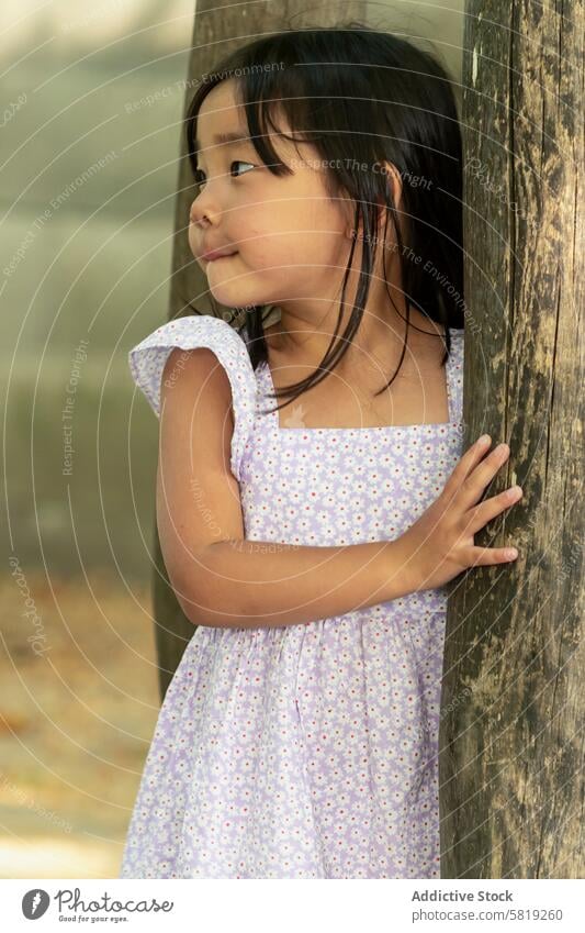 Asiatisches Kleinkind Mädchen in einem verspielten Sommerkleid im Freien Kind asiatisch Urlaub Europa Kleid spielerisch Baum nachdenklich Kindheit Park reisen