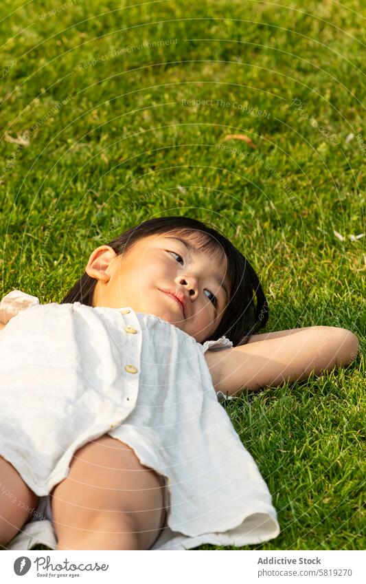 Asiatisches Kind entspannt sich im Gras während der europäischen Ferien asiatisch Mädchen entspannend Urlaub Europa Freizeit Feiertag Familie Freude verträumt
