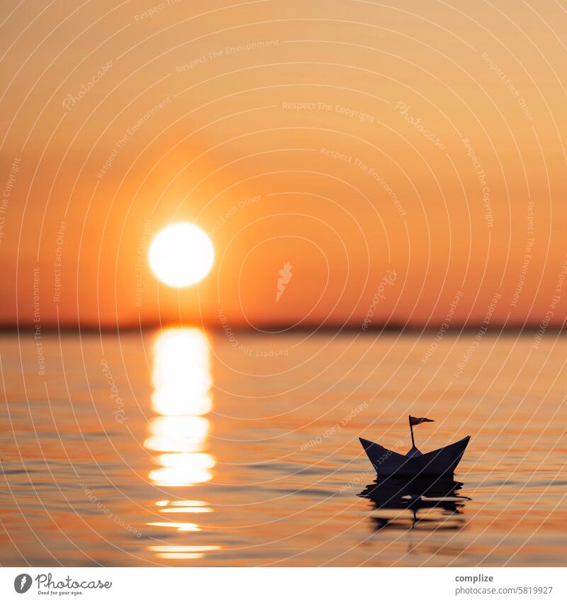 Kleines Papierschiff fährt auf einem See in Finnland in den Sonnenuntergang sonne see meer wasser wellness relaxen ruhe abendrot boot orange schwimmen