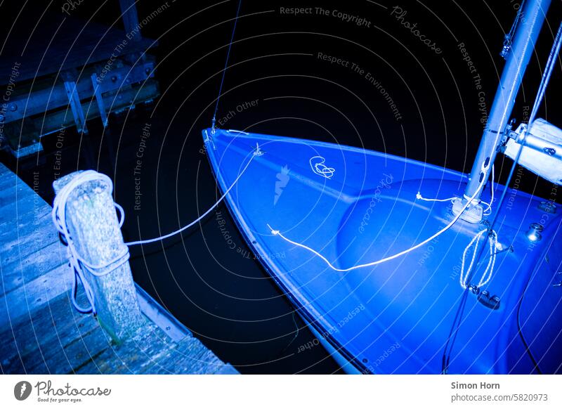 Bug eines kleinen Segelschiffes liegt nachts vertaut an einem Holzsteg Schiff Nacht blau schwarz Dunkelheit Ferien & Urlaub & Reisen Wasser Segelboot konturlos