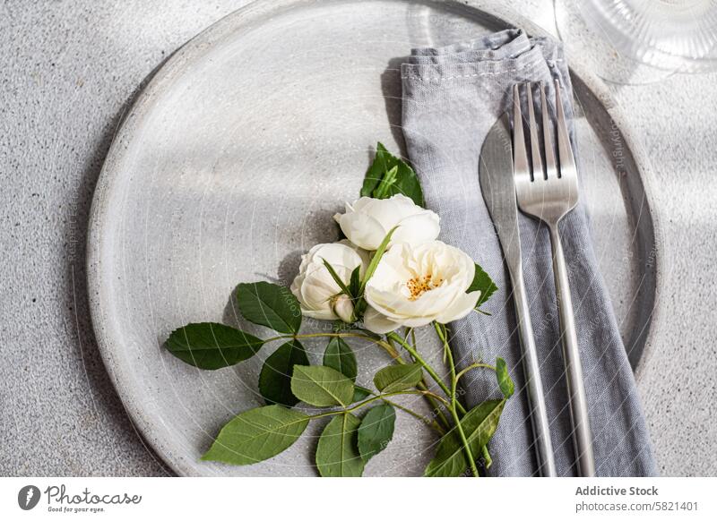 Elegante neutrale Tischdekoration mit frischen weißen Rosen Einstellung Roséwein Keramik Teller Silber Besteck Leinen Serviette Blume Ordnung Hochzeit elegant