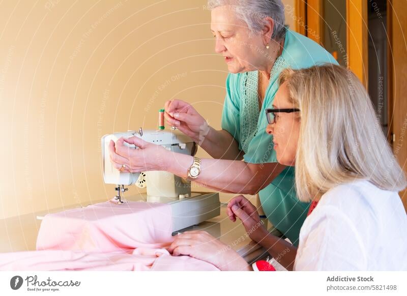 Ältere Frau unterrichtet Nähtechniken Werkstatt Nähen Lehre Lernen Senior Maschine Gewebe Faser Spule Nadel Handwerk Hobby Belehrung Fähigkeit Anleitung Schüler