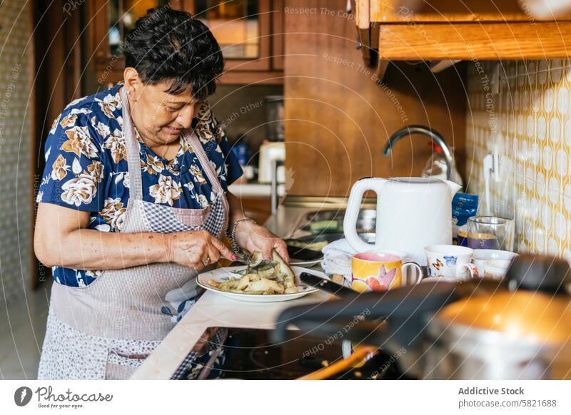 Ältere Frau bei der Zubereitung einer Mahlzeit in ihrer Küche Senior Essen zubereiten heimwärts älter Lebensmittel Vorbereitung gemütlich heimisch Innenbereich