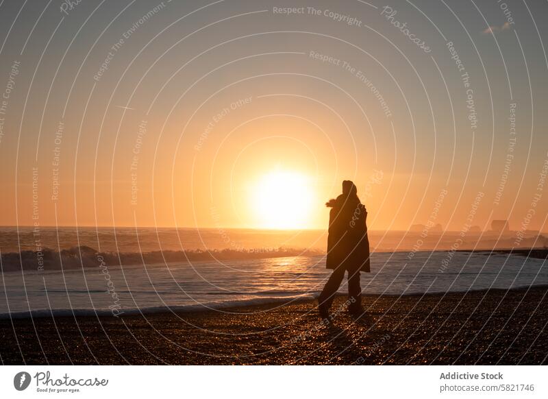 Silhouette einer Person, die bei Sonnenaufgang in Island am Strand spazieren geht laufen MEER Horizont winken Ufer ruhig Gelassenheit Morgen Licht hell glühen
