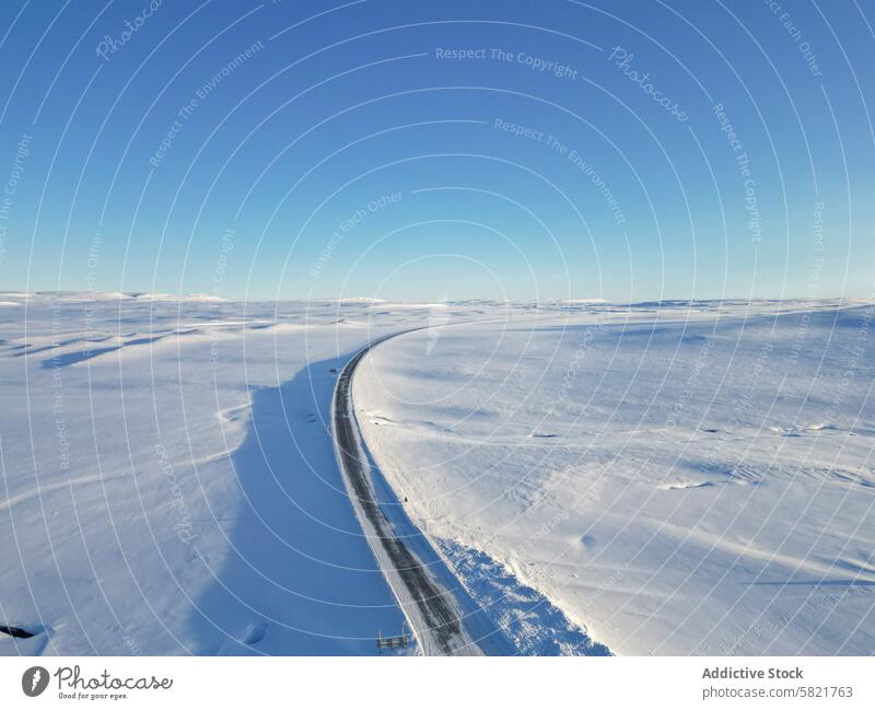 Kurvenreiche Straße inmitten einer ausgedehnten Schneelandschaft in Island Landschaft Luftaufnahme Einsamkeit Natur Winter Klarer Himmel blau kalt arktische