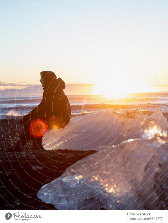 Silhouettierte Figur, die an einer sonnenbeschienenen isländischen Küste kontempliert Island Silhouette Sonnenuntergang Strand Eis Kontemplation Natur