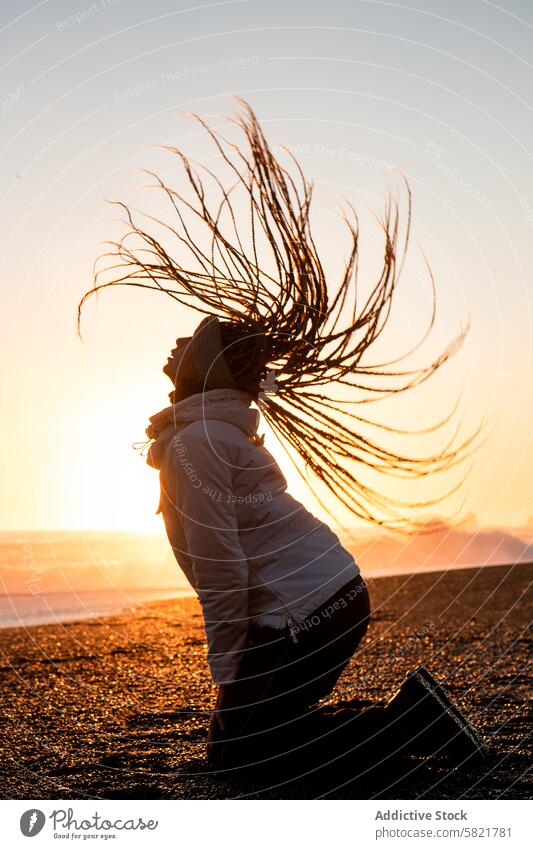 Frau mit wallendem Haar bei Sonnenuntergang an einem isländischen Strand Silhouette Island Wind Behaarung dramatisch Gelassenheit glühend Horizont Meer Winter