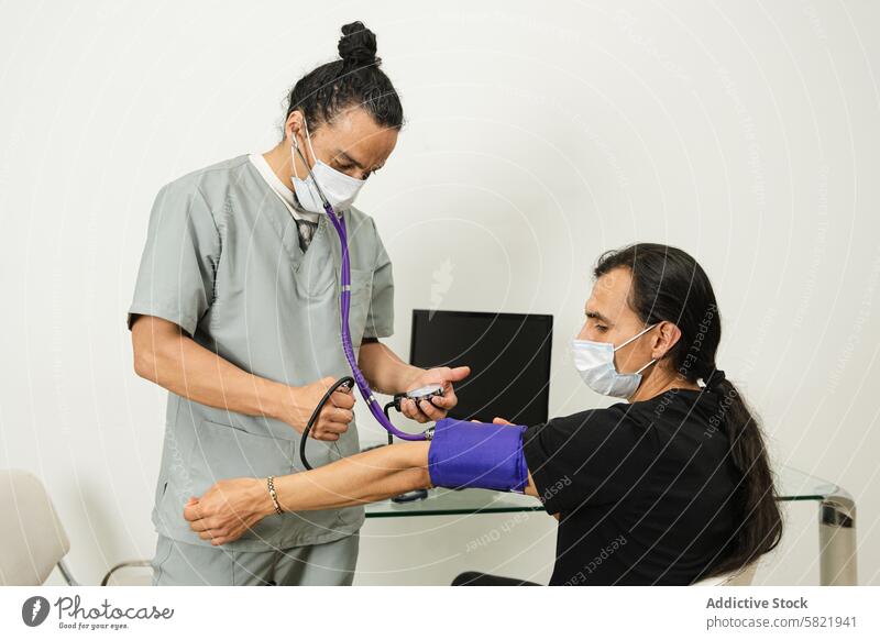 Krankenschwester prüft den Blutdruck eines Patienten in einer medizinischen Einrichtung Krankenpfleger geduldig Gesundheitswesen Mundschutz klinisch Prüfung