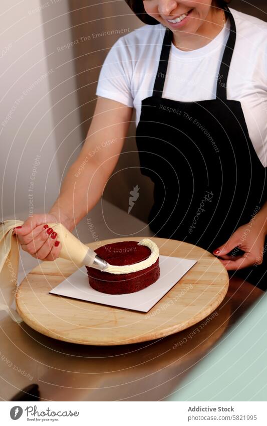 Glasur auf einen roten Samtkuchen auftragen Frau Zuckerguss Kuchen dekorierend Spritzbeutel Schürze backen roter Samt Küche Dessert Gebäck Kochen Zuckerguß