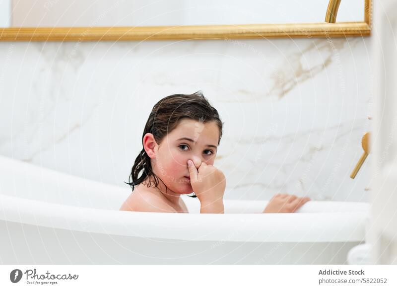 Junges Mädchen, das zu Hause im Bad spielt und in die Kamera schaut Kind Badewanne spielen heimwärts nasses Haar in die Kamera schauen im Innenbereich Hygiene