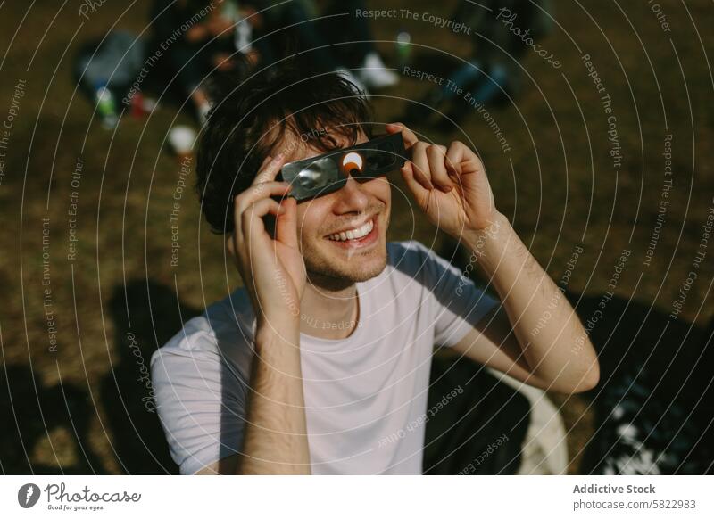 Junger Mann mit Fernglas in einem sonnigen Park jung Sonne Gras im Freien Freunde Tag Freizeit Natur Lächeln Glück heiter männlich jugendlich lässig