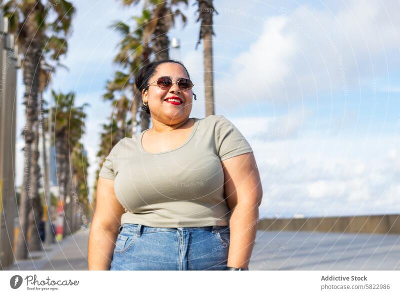 Lächelnde Frau, die einen sonnigen Tag in Barcelona genießt Sommer Spazierweg Palme schlendern Freude Freunde Glück heiter Sonnenschein Afroamerikaner