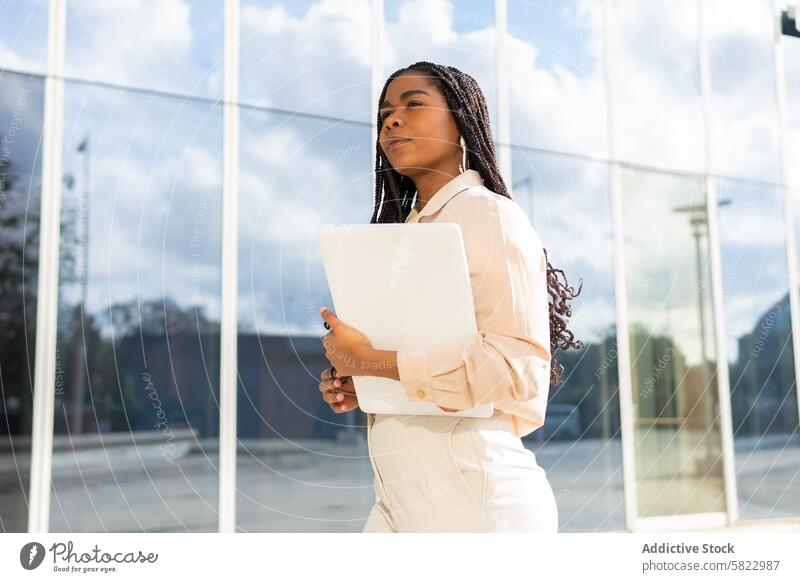 Geschäftsfrau mit Laptop vor einem modernen Gebäude Frau Bürogebäude professionell selbstbewusst Ehrgeiz Erfolg Glas Zeitgenosse im Freien Karriere Arbeit