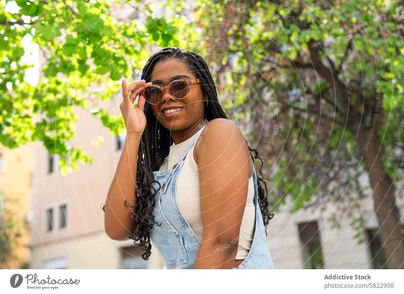 Fröhliche Frau genießt den Sommer in den Straßen von Barcelona Sonnenbrille Lächeln heiter Glück sonnig Grün sorgenfrei jung Mode lässig Afroamerikaner schwarz
