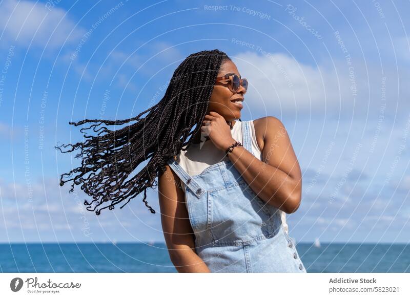 Fröhlicher Sommertag am Meer in Barcelona Frau MEER Küstenlinie sonnig Blauer Himmel Jeansstoff Latzhose Brille Lächeln Glück Frisur Zopf Afrikanisch Jugend