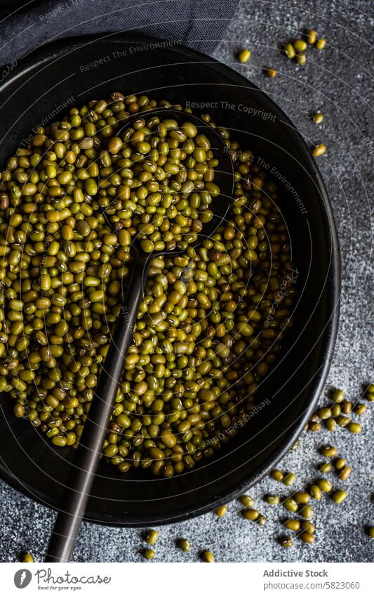 Nahaufnahme von rohen Bio-Mungbohnen in einer Pfanne Bohne mung organisch Löffel dunkel rustikal Hülsenfrüchtler grün Haufen Essen zubereiten Bestandteil