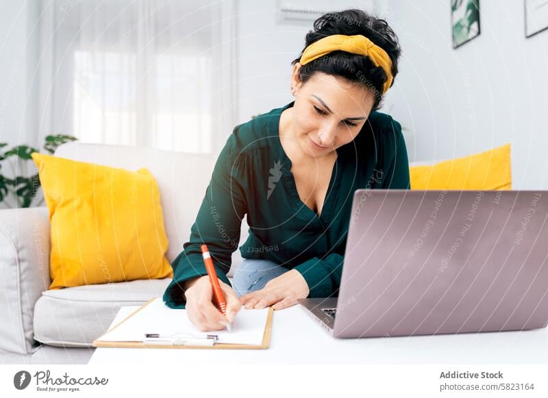 Frau arbeitet von zu Hause aus mit Laptop und Notizbuch arbeiten heimwärts Notebook schreibend Büro abgelegen Job freiberuflich Computer Technik & Technologie