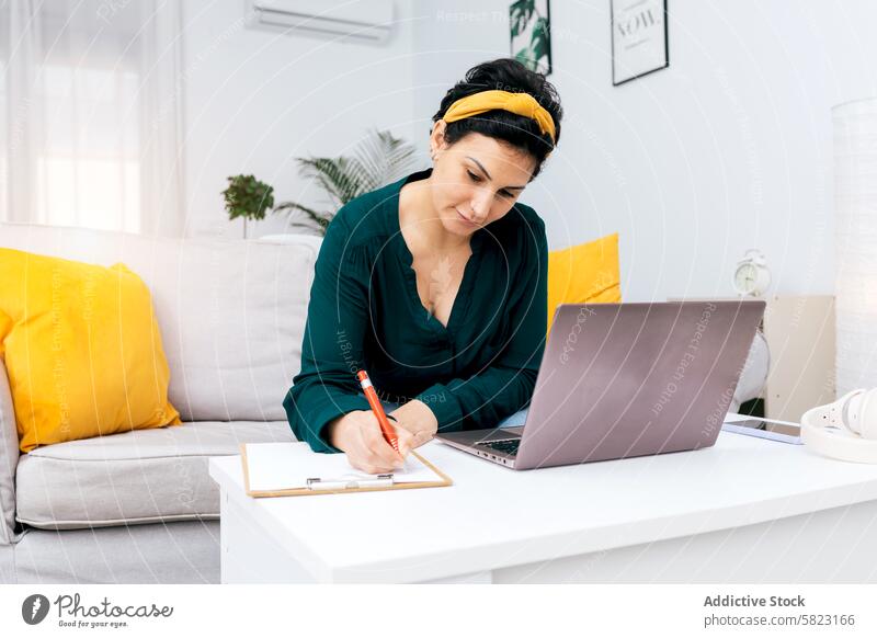 Frau arbeitet von zu Hause aus und erstellt Inhalte Laptop heimwärts Schreibtisch schreibend Hinweis Büro Vorrat Dekor hell gemütlich Arbeit im Innenbereich